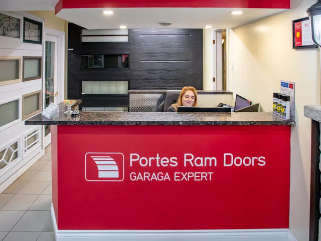 Portes Ram Doors reception desk with our receptionist with garage door samples on the back to answer all your questions